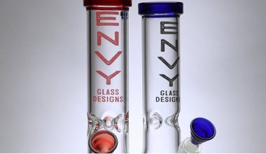 Two translucent glass bongs labelled 'Envy Glass Designs' with respective red and blue rims, text and mouthpieces